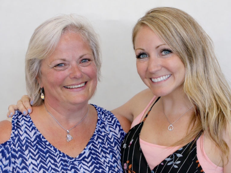 Portrait of two smiling female clinic professionals standing together on the Ajax Family Physiotherapy team page.