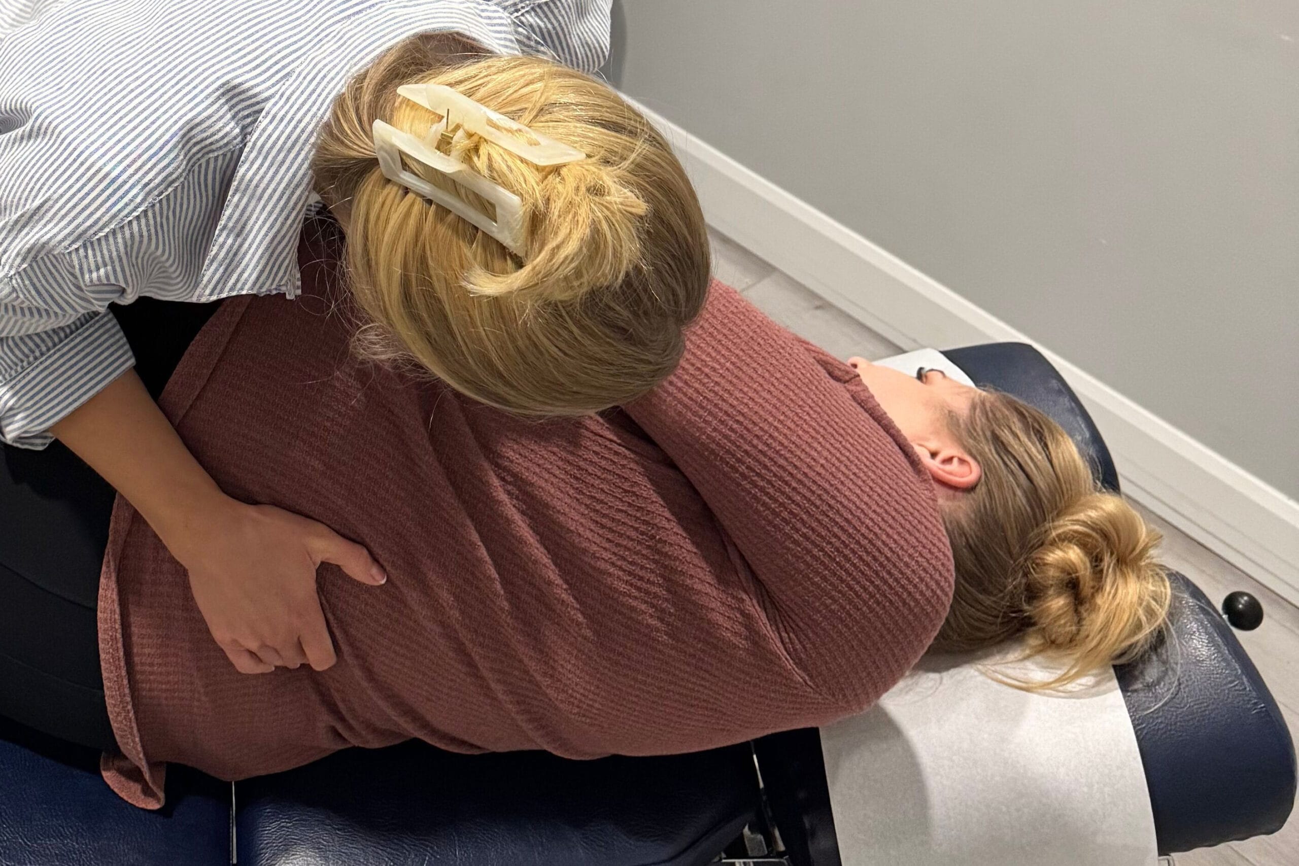 A chiropractor performing a manual spinal adjustment on a patient lying on a treatment table.