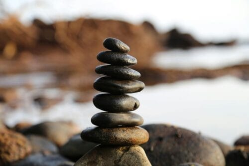 A perfectly balanced stack of smooth dark zen stones on a rocky beach, symbolizing natural health and wellness.