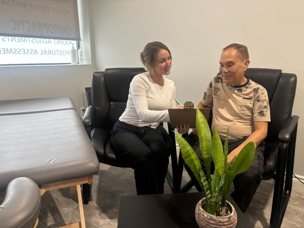 A friendly female clinician reviewing an intake form on a clipboard with a male patient during an initial clinic consultation.